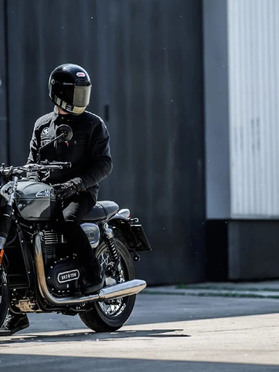 A rider on the Cromwell 1200 beside a corrugated steel wall